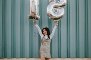 Young girl holding balloons for her 18th birthday. Photo by Hannah Busing on Unsplash